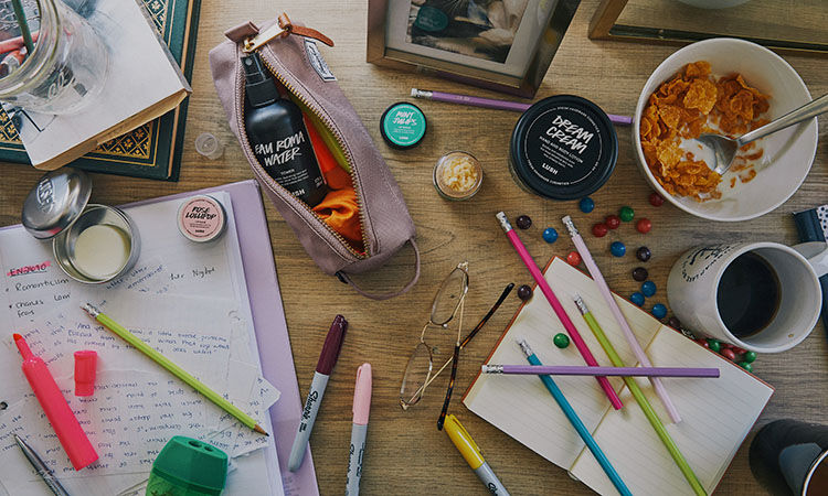 Lush products and school supplies scattered on a desk.