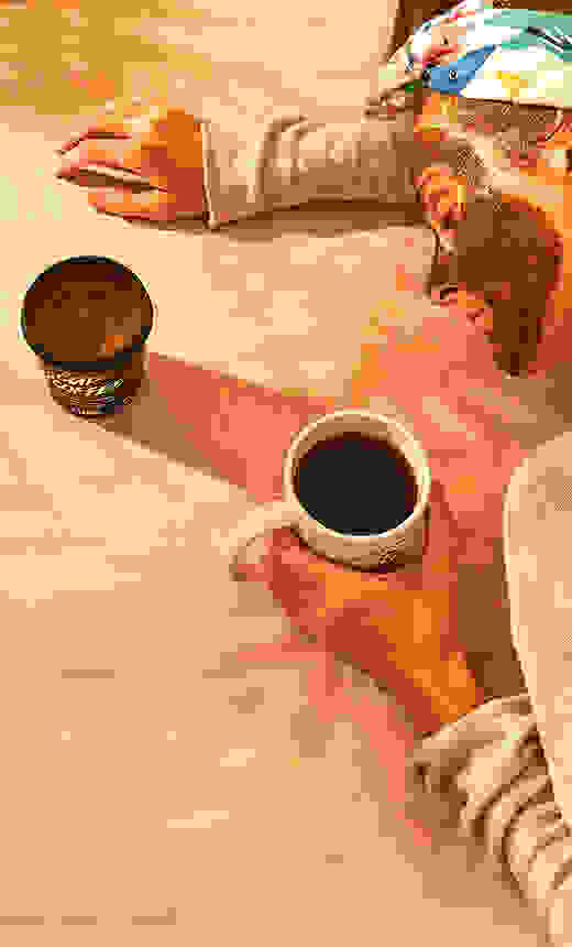 A woman lying on a countertop with a cup of coffee in hand